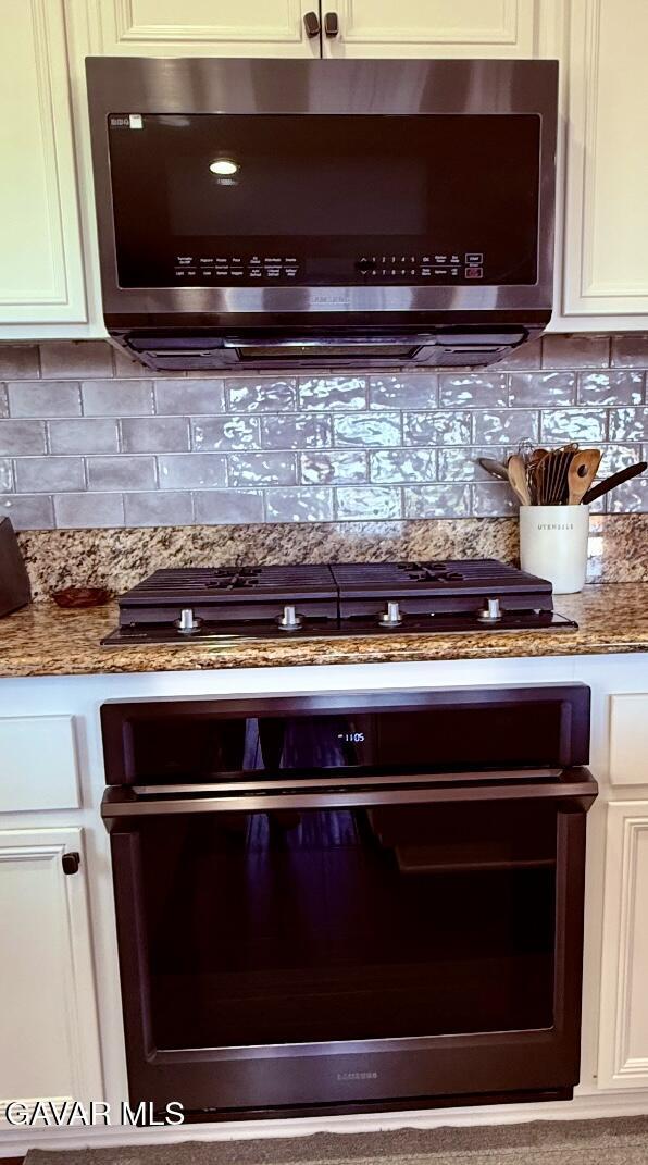4011 Prestwick Ln, Palmdale, CA 93551 - kitchen view of black appliances, backsplash, light stone counters, and white cabinets