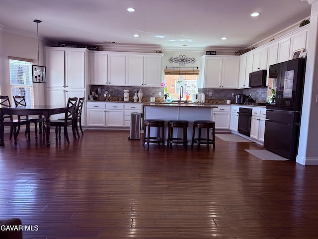 4011 Prestwick Ln, Palmdale, CA 93551 - kitchen with black appliances, a breakfast bar, white cabinets, crown molding, and a center island