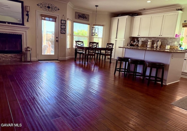 4011 Prestwick Ln, Palmdale, CA 93551 - kitchen featuring white cabinets, dark wood-type flooring, crown molding, hanging light fixtures, and a kitchen bar