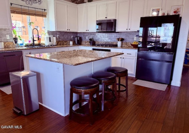 4011 Prestwick Ln, Palmdale, CA 93551 - kitchen featuring stainless steel microwave, refrigerator, a kitchen island, dark wood-style flooring, and backsplash