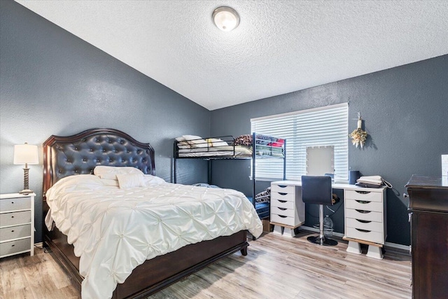 bedroom featuring wood finished floors, lofted ceiling, and a textured wall