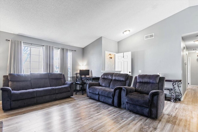 living area with visible vents, lofted ceiling, a textured ceiling, and wood finished floors