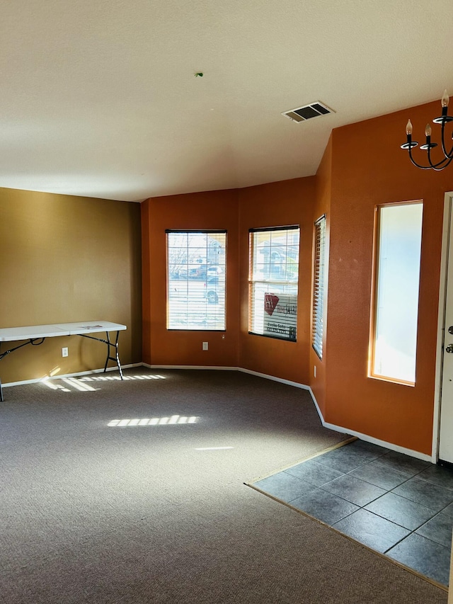 carpeted empty room with an inviting chandelier