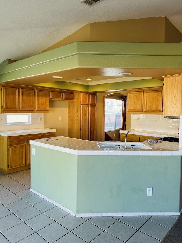 kitchen with tile counters, light tile patterned flooring, a textured ceiling, and tasteful backsplash