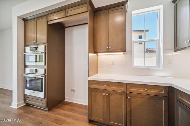 39635 Nicholas Ct, Palmdale, CA 93551 - kitchen with tasteful backsplash, dark wood-type flooring, stainless steel double oven, and light countertops