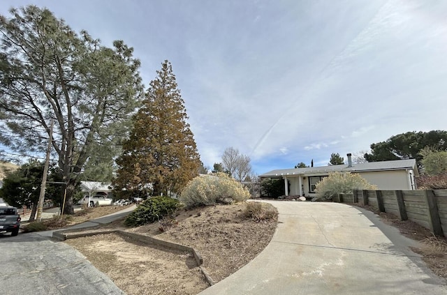 ranch-style home with concrete driveway and fence