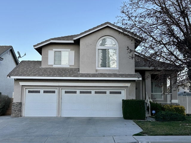 traditional-style home featuring stucco siding, driveway, and an attached garage