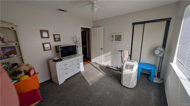 bedroom featuring dark colored carpet, ceiling fan, and a closet