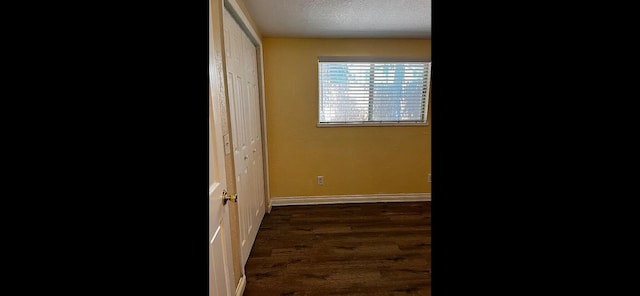 corridor with dark hardwood / wood-style floors and a textured ceiling