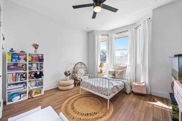 bedroom featuring baseboards, wood finished floors, and a ceiling fan