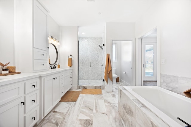 bathroom featuring vanity, a bath, a stall shower, toilet, and marble finish floor