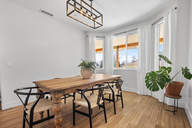 dining space featuring an inviting chandelier, light wood-style floors, visible vents, and baseboards