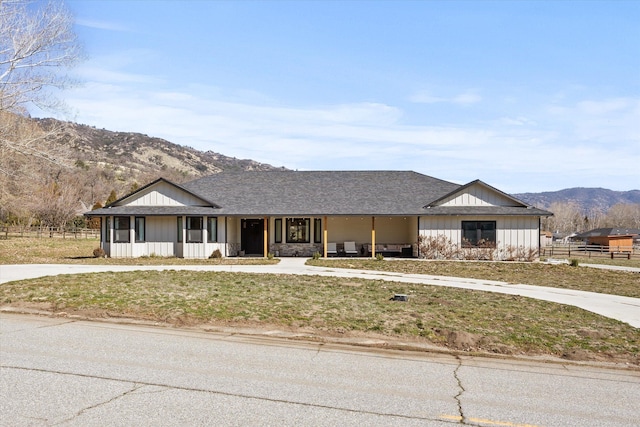 view of front of property featuring fence, a mountain view, board and batten siding, roof with shingles, and covered porch