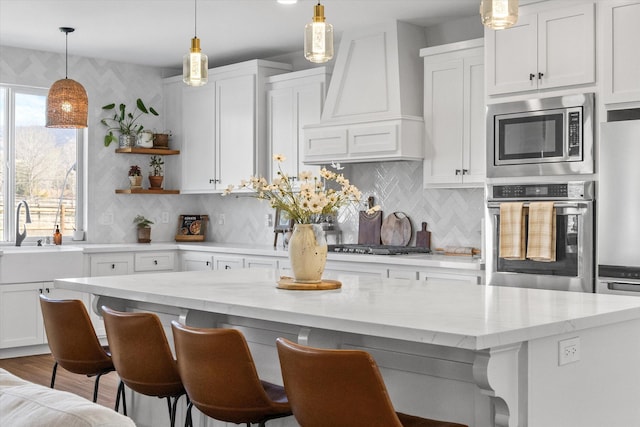 kitchen with white cabinets, open shelves, stainless steel appliances, and premium range hood