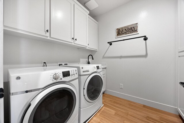 clothes washing area featuring baseboards, cabinet space, a sink, washer and dryer, and light wood-type flooring