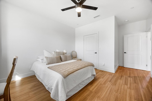 bedroom featuring light wood-type flooring, visible vents, baseboards, and ceiling fan