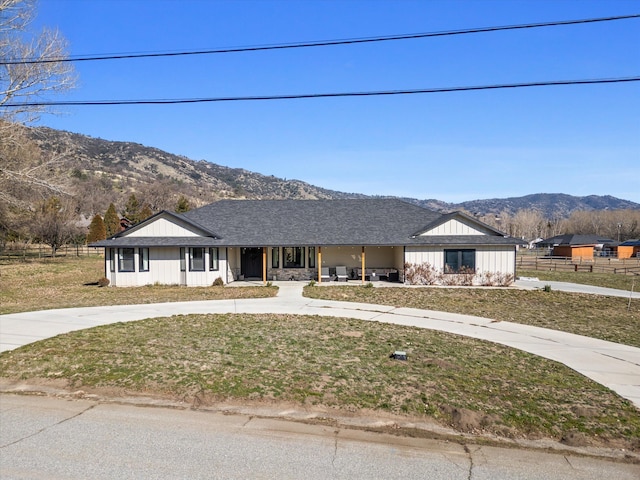 view of front of property with a mountain view, driveway, a front yard, and roof with shingles