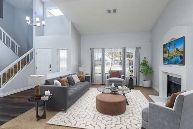 living room featuring a towering ceiling, wood-type flooring, and a chandelier