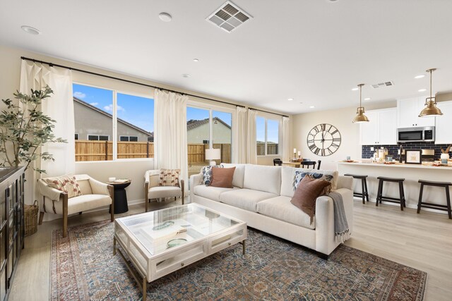 living area with recessed lighting, light wood finished floors, and visible vents