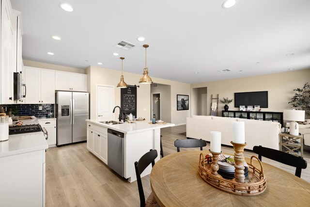 kitchen with a sink, appliances with stainless steel finishes, visible vents, open floor plan, and light wood-style floors