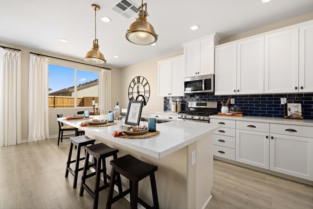 kitchen featuring light countertops, appliances with stainless steel finishes, tasteful backsplash, and light wood-style flooring