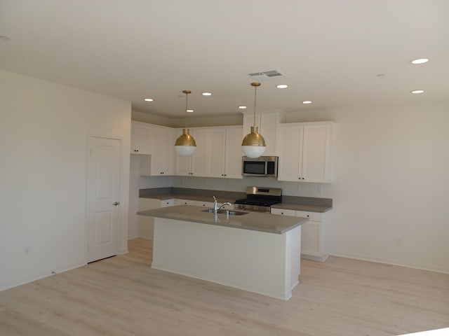 kitchen with stainless steel appliances, light wood-style flooring, visible vents, and a center island with sink