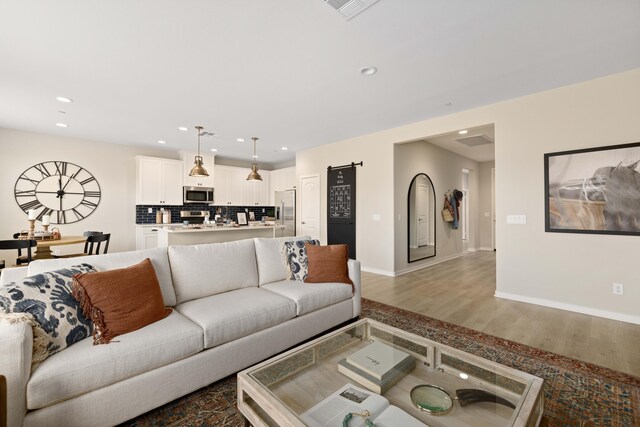 living room featuring recessed lighting, baseboards, visible vents, and wood finished floors