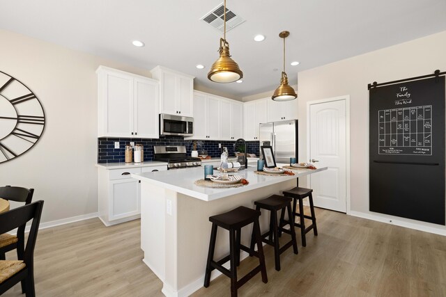 kitchen featuring stainless steel appliances, visible vents, light wood finished floors, backsplash, and light countertops