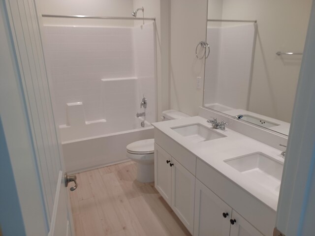 bathroom with toilet, bathing tub / shower combination, a sink, and wood finished floors
