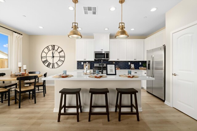 kitchen with light countertops, appliances with stainless steel finishes, decorative backsplash, and visible vents