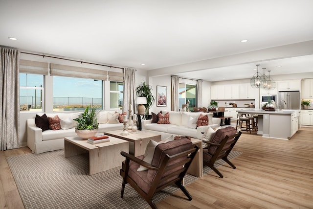 living room with a chandelier, sink, and light hardwood / wood-style flooring