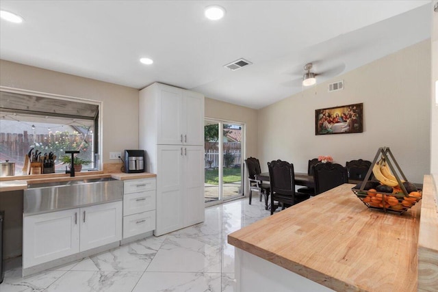 kitchen featuring wood counters, ceiling fan, sink, white cabinetry, and lofted ceiling