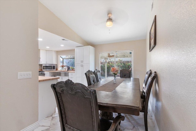 dining space with ceiling fan, vaulted ceiling, and a wealth of natural light