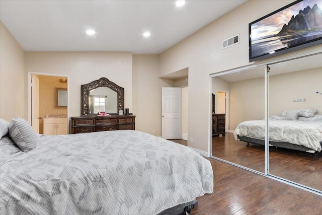 bedroom with sink, lofted ceiling, a closet, dark hardwood / wood-style floors, and ensuite bath