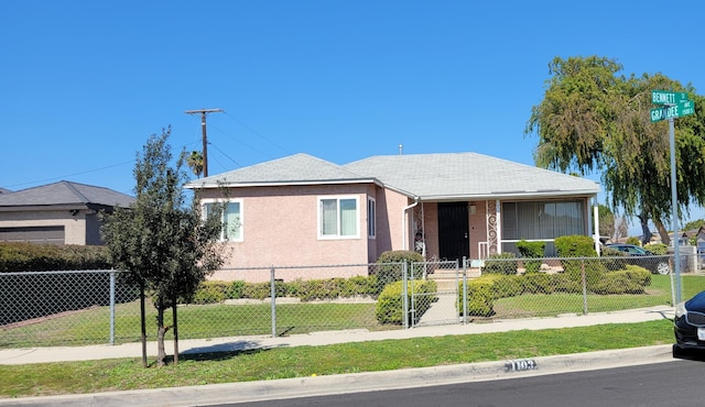 bungalow with a fenced front yard, stucco siding, and a front yard