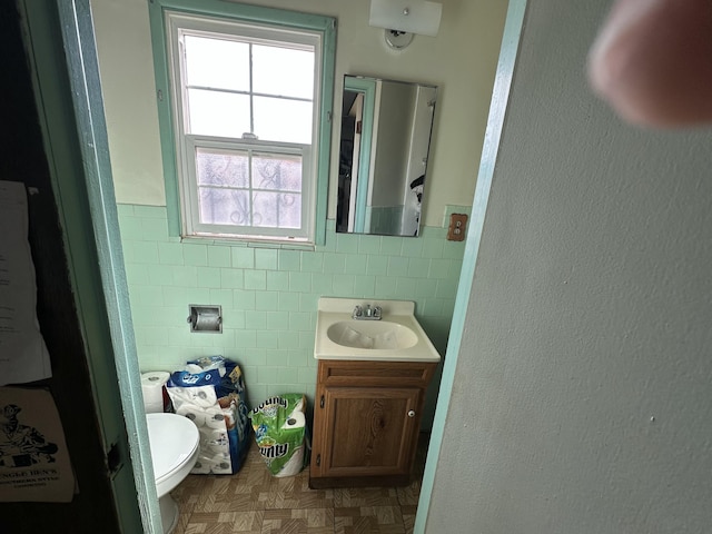 bathroom with vanity, tile walls, parquet floors, and toilet