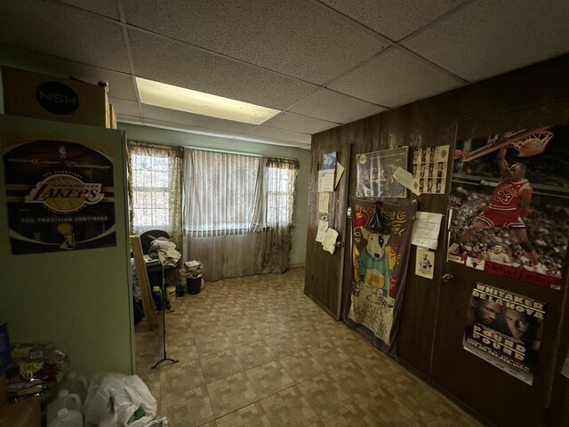 interior space featuring a drop ceiling and wooden walls