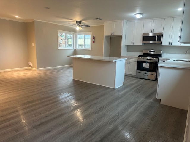 kitchen with a sink, appliances with stainless steel finishes, ornamental molding, and white cabinetry