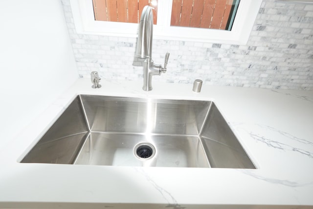 details featuring sink, backsplash, and light stone countertops