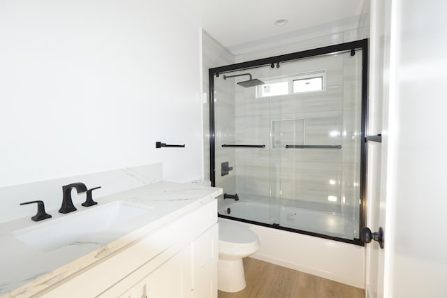 full bathroom with vanity, combined bath / shower with glass door, hardwood / wood-style floors, and toilet