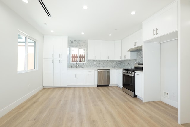 kitchen featuring sink, plenty of natural light, stainless steel appliances, decorative backsplash, and white cabinets