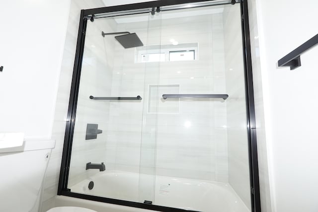 bathroom featuring bath / shower combo with glass door and toilet