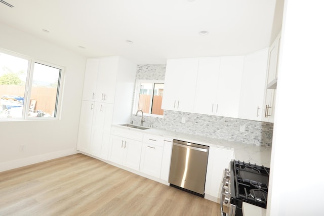 kitchen with appliances with stainless steel finishes, sink, backsplash, white cabinets, and light stone counters