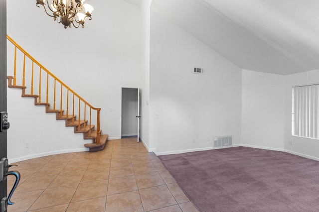 tiled entryway featuring a chandelier and high vaulted ceiling