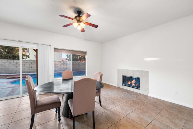 tiled dining area featuring a tile fireplace and ceiling fan