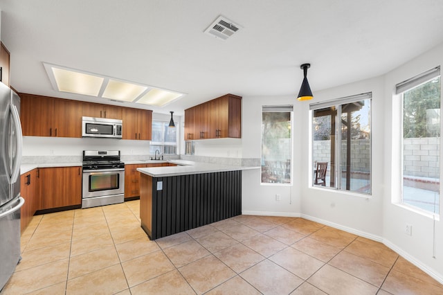 kitchen featuring sink, light tile patterned floors, hanging light fixtures, stainless steel appliances, and kitchen peninsula