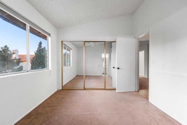 unfurnished bedroom featuring vaulted ceiling, carpet floors, a water view, a textured ceiling, and a closet