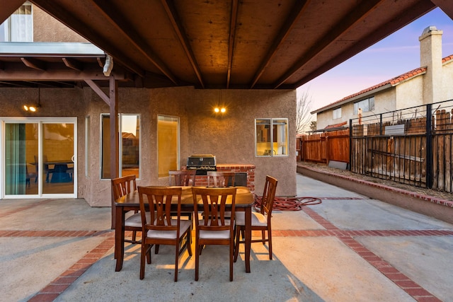 patio terrace at dusk featuring a grill