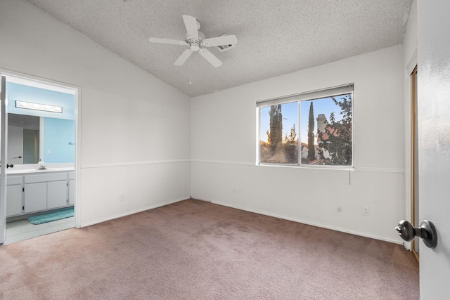 unfurnished bedroom featuring ceiling fan, carpet flooring, connected bathroom, a textured ceiling, and vaulted ceiling