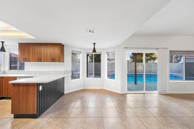 kitchen with decorative light fixtures, kitchen peninsula, a breakfast bar area, and light tile patterned floors